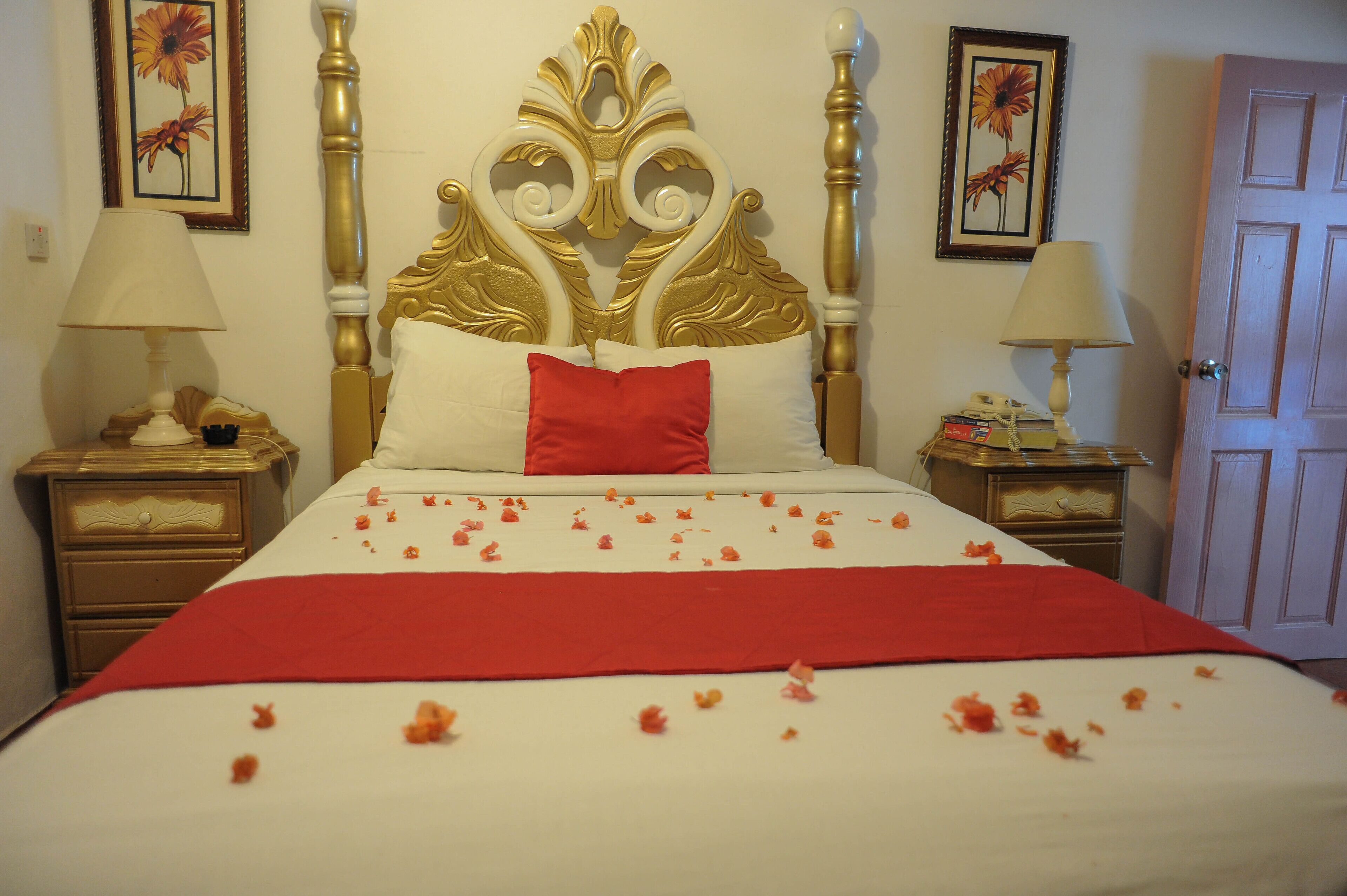 Une chambre d’hôtel avec un grand lit, un plaid rouge et une tête de lit décorative.