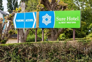 A hotel sign with directions to parking and the hotel entrance, and the name 'Sure Hotel by Best Western'. - Sure Hotel by Best Western Port Jerome - Le Havre (Port-Jérôme-sur-Seine)