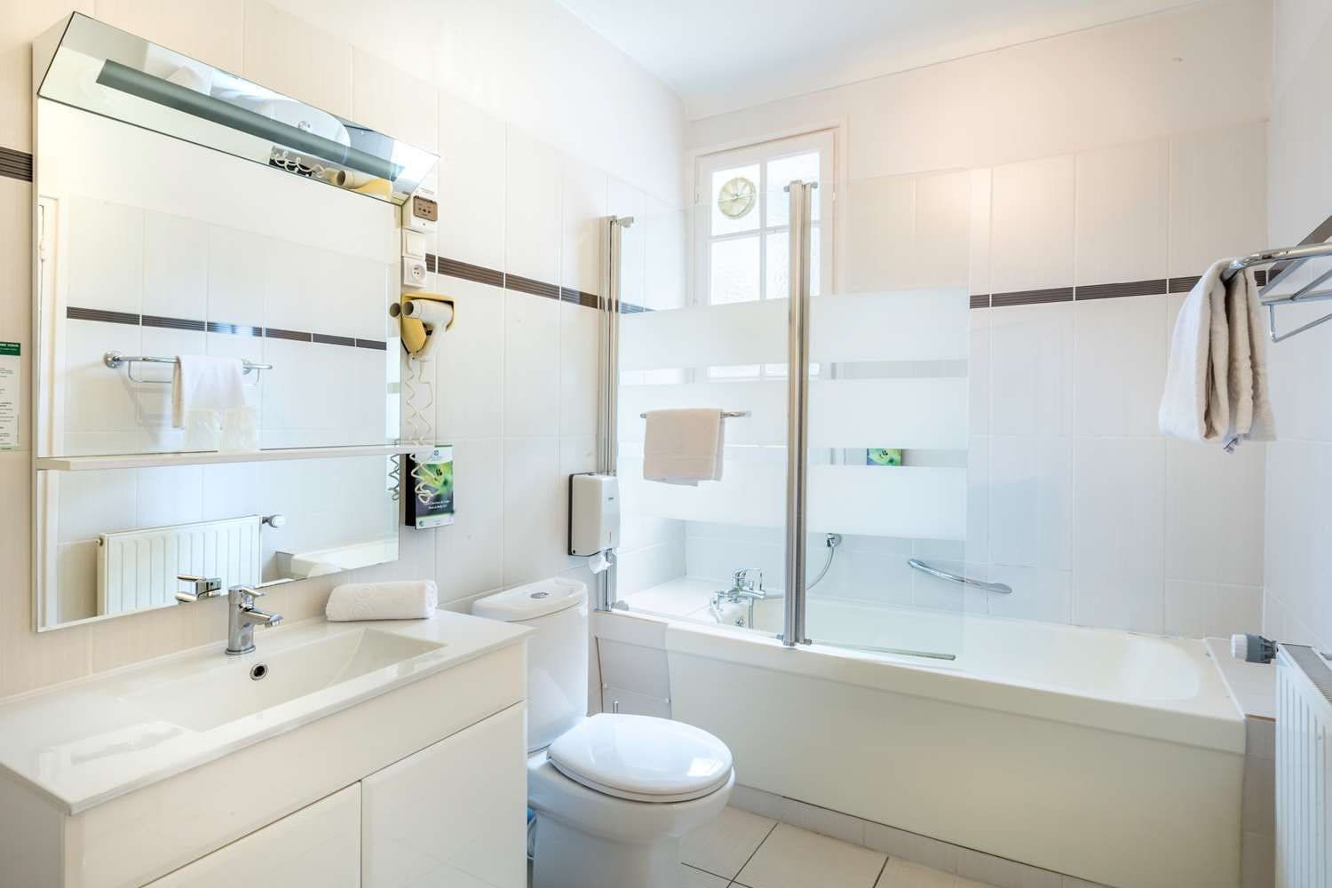 Une salle de bain moderne équipée d’une baignoire, de toilettes et d’une douche à parois de verre.