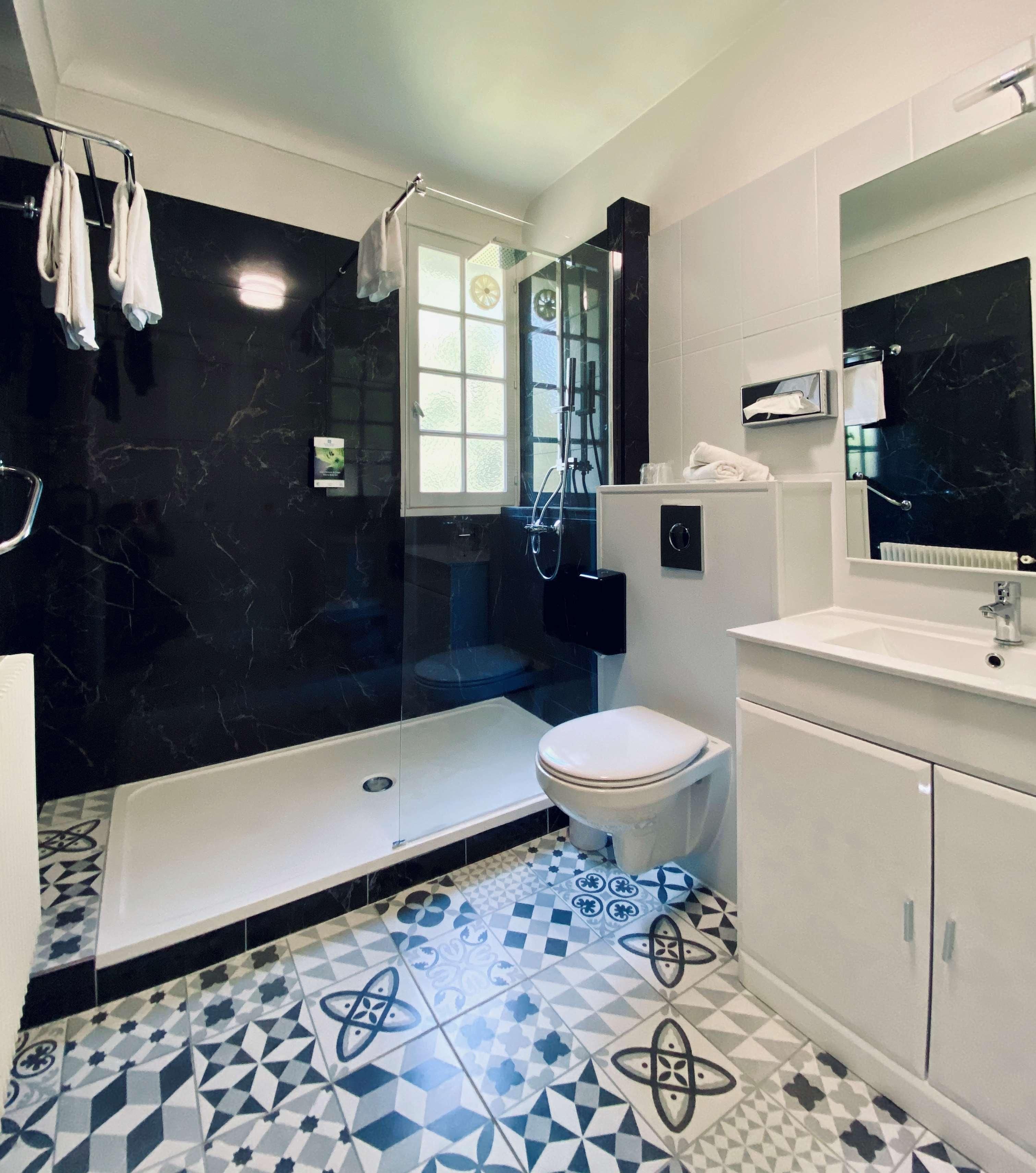 A modern bathroom with a shower, toilet, and sink.