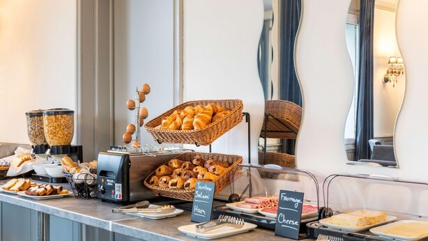 A buffet counter with various food items including bread, ham, and cheese. - Sure Hotel by Best Western Port Jerome - Le Havre (Port-Jérôme-sur-Seine)