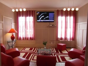 A living room with red furniture, a TV on the wall, and a patterned rug. - Sure Hotel by Best Western Port Jerome - Le Havre (Port-Jérôme-sur-Seine)