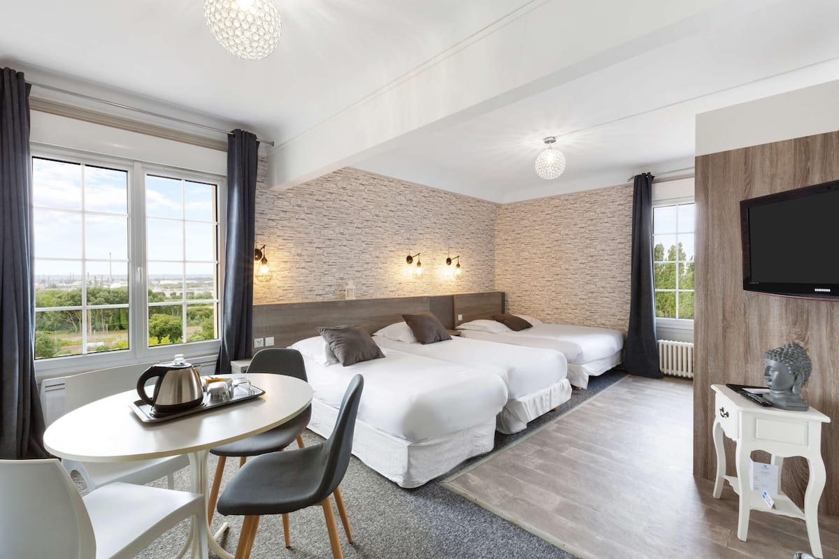 Une chambre d’hôtel avec deux lits, une table à manger, un téléviseur et une vue sur l’extérieur.