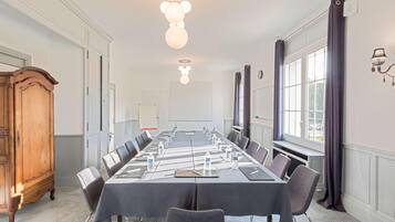 A conference room with a long table, chairs, water bottles, and a wooden cabinet.