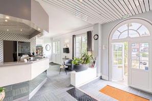 Un hall d’hôtel moderne doté d’un comptoir d’accueil, d’un espace salon et de grandes fenêtres offrant une vue sur l’extérieur.