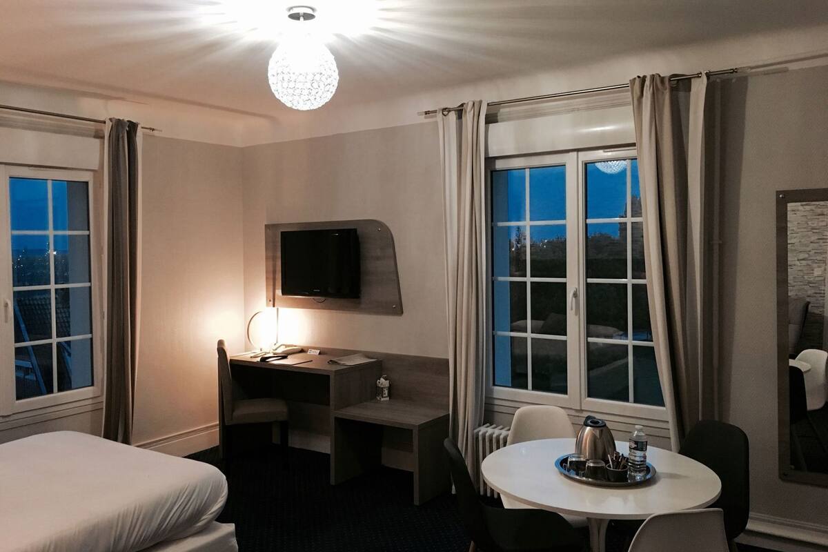 Une chambre d’hôtel équipée d’un lit, d’un bureau, d’une chaise, d’une télévision et d’une table avec un plateau.