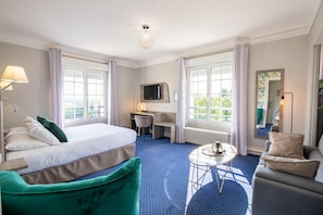 Une chambre d’hôtel avec un lit, un bureau, une chaise, une petite table et un téléviseur.