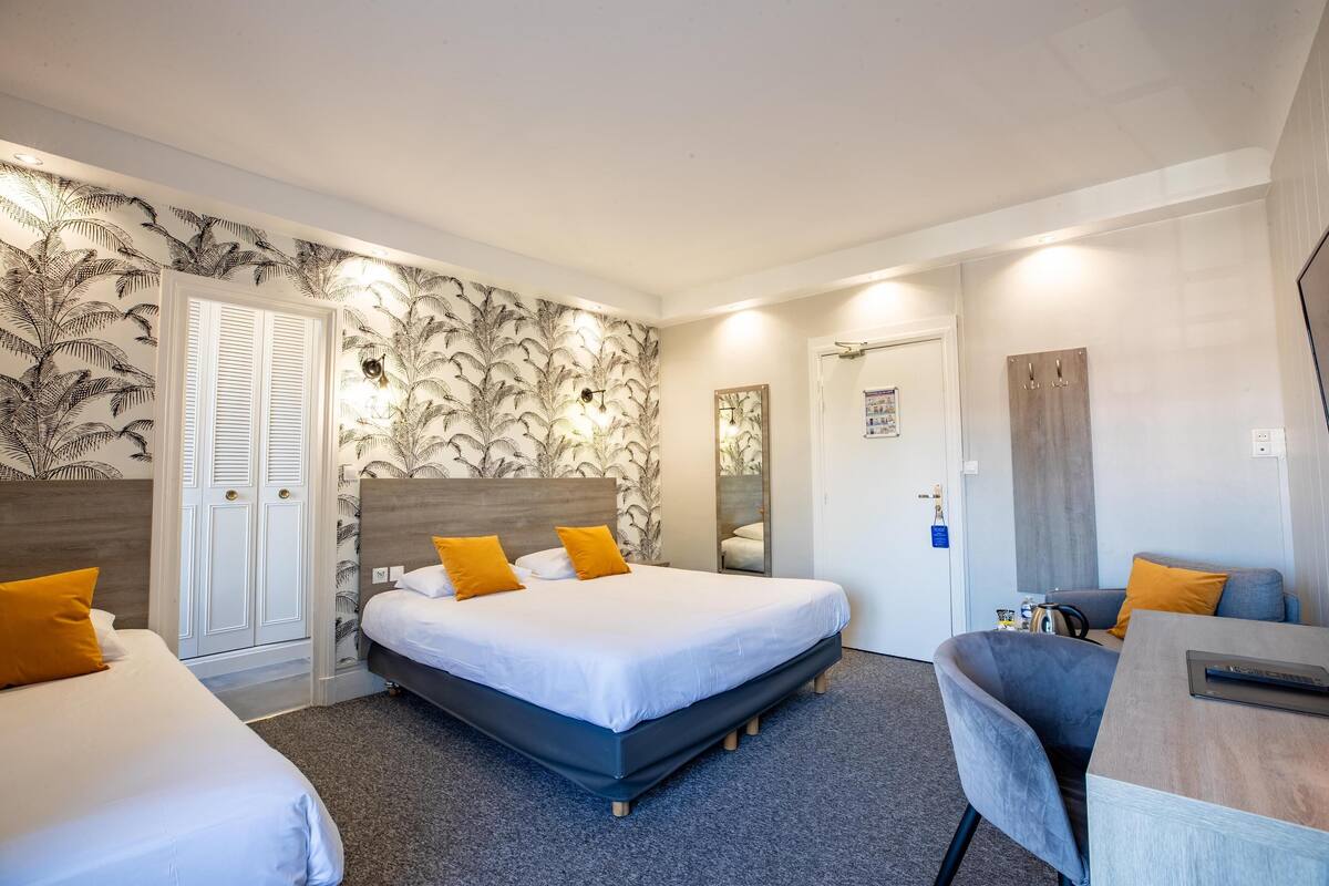 Une chambre d’hôtel avec un grand lit, deux tables de chevet, un bureau et une chaise.