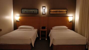 Habitación de hotel con dos camas, una mesita de noche y dos lámparas de pared.