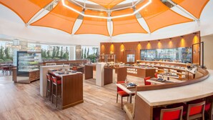 A modern restaurant with a central island, wooden flooring, and orange canopy lighting. - Hyatt Place Hyderabad Banjara Hills (Hyderabad)