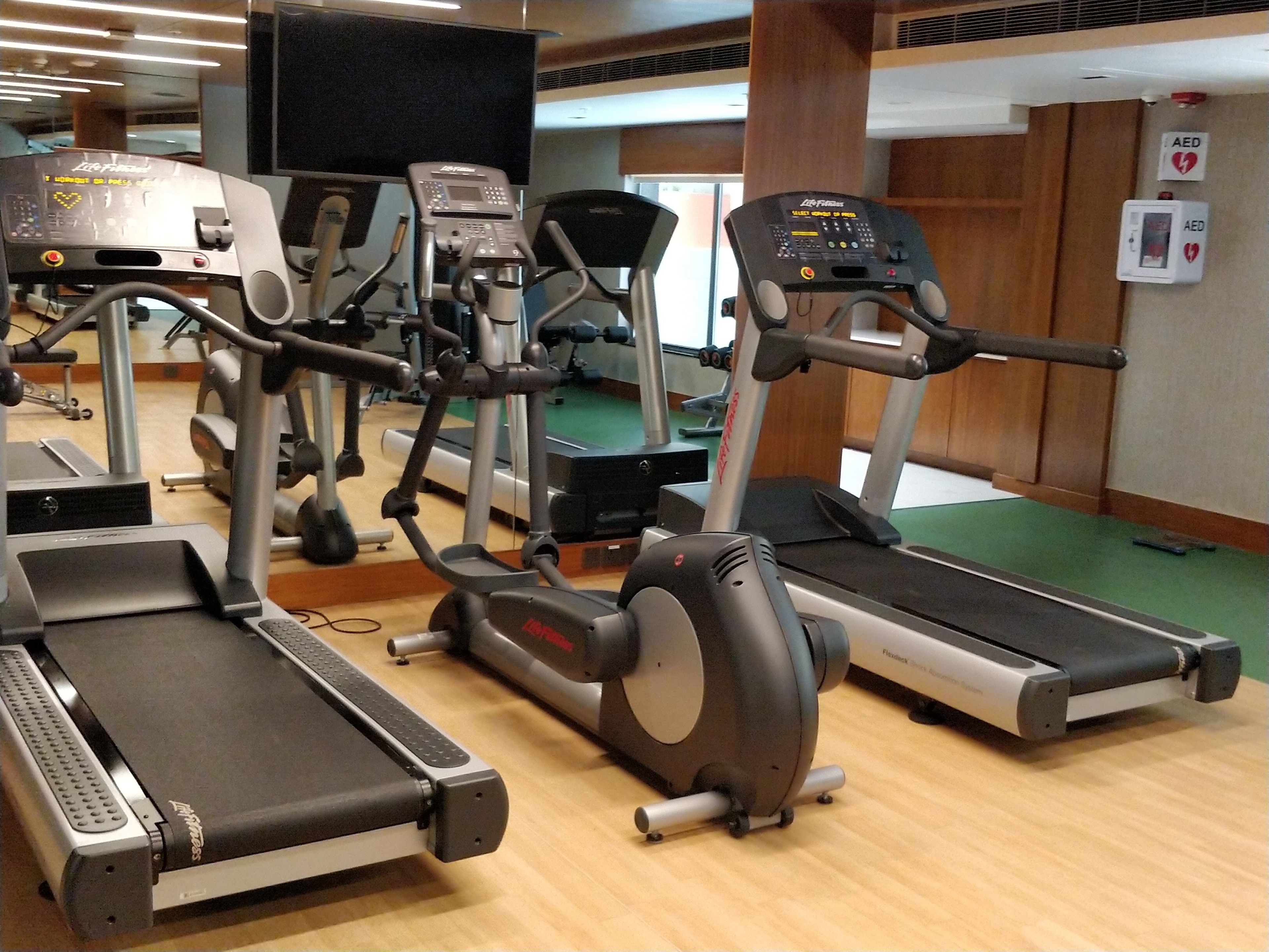Un gimnasio con cintas de correr, elípticas y una bicicleta estática.
