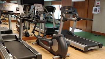 Un gimnasio con cintas de correr, elípticas y una bicicleta estática.