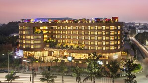 A multi-story hotel with a curved facade, multiple balconies, and a rooftop bar. - Hyatt Place Hyderabad Banjara Hills (Hyderabad)