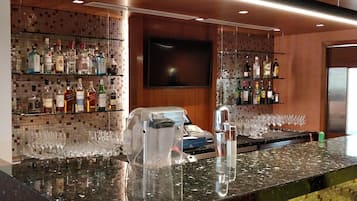 A bar area with a polished granite countertop, a cash register, and a variety of liquor bottles on shelves.