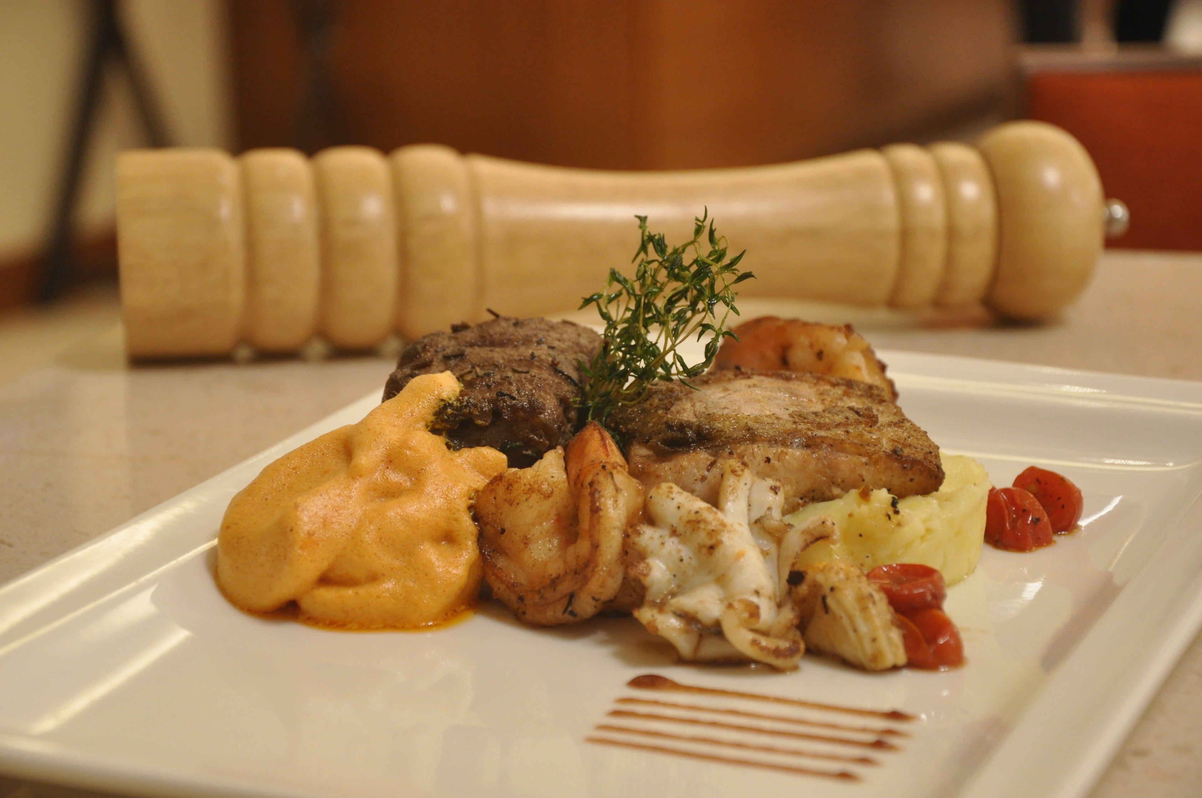 Un plato de comida con varios elementos, incluyendo carne, puré de papas y verduras.