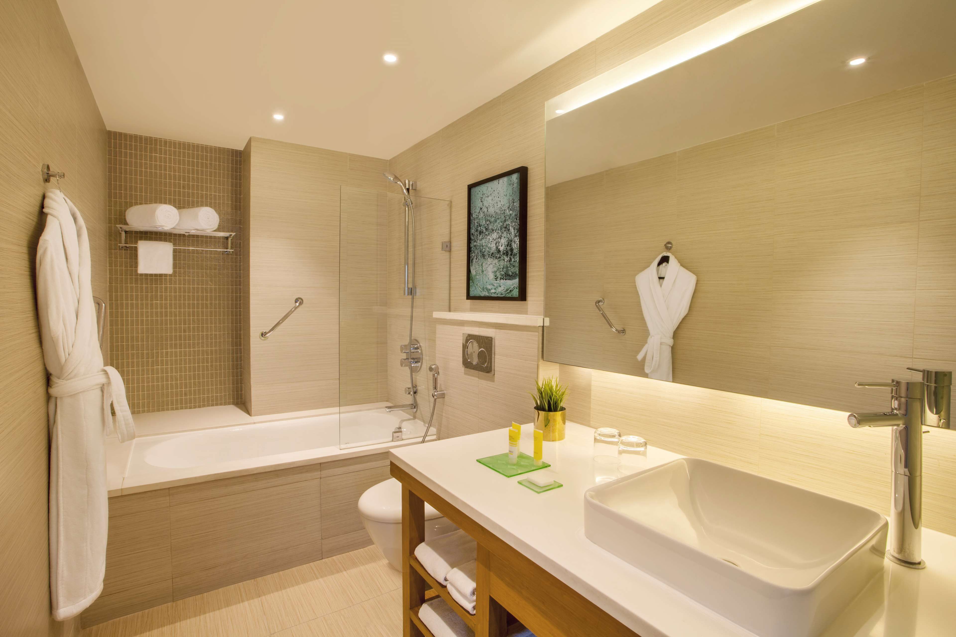 Een moderne badkamer met een bad, een grote spiegel, een wastafel en een douche.