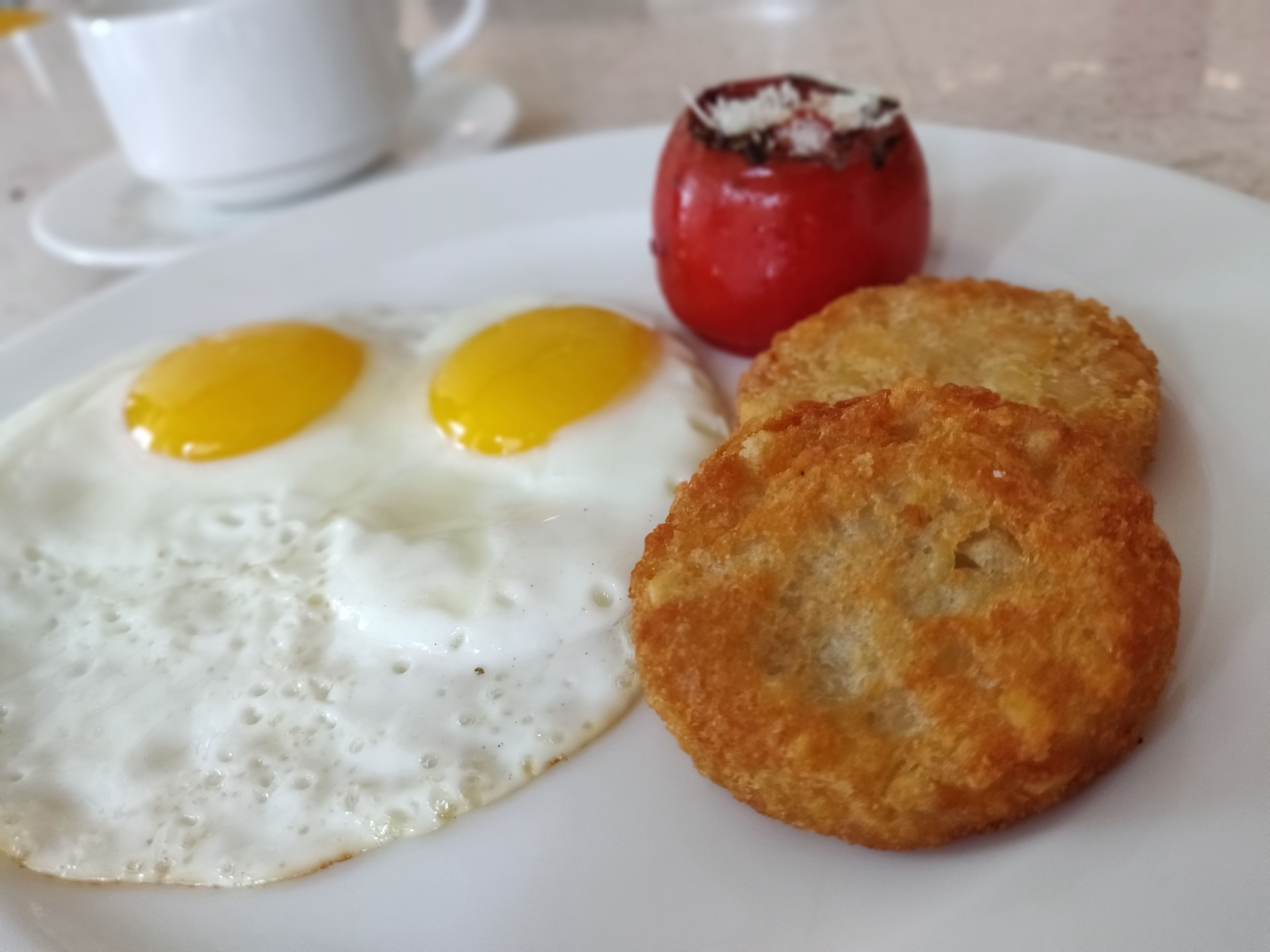A breakfast plate with two fried eggs and a fried patty.