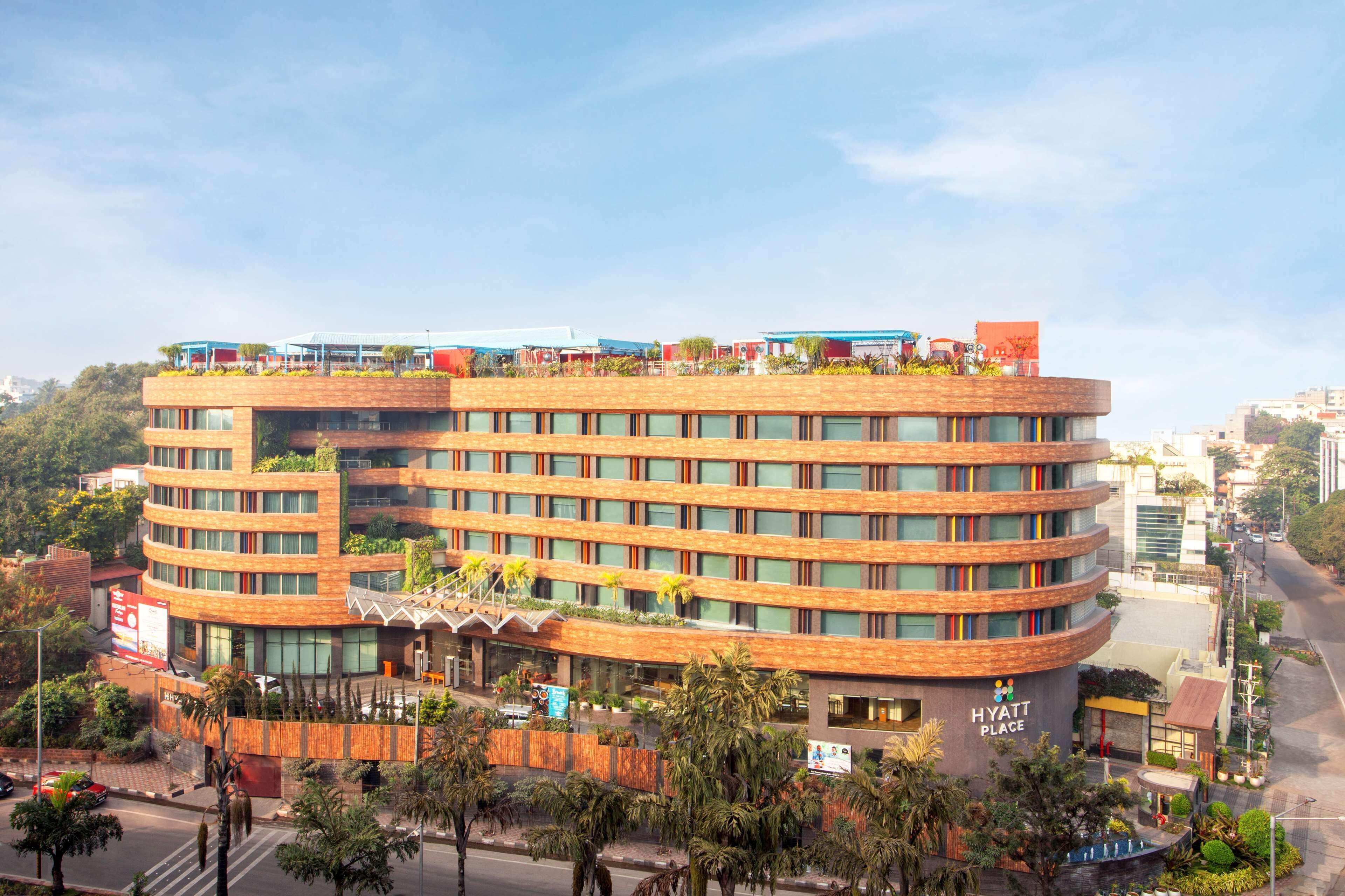 Un hotel de varios pisos con una fachada curva, zonas de estar al aire libre y una señal visible que indica que es un Hyatt Place.