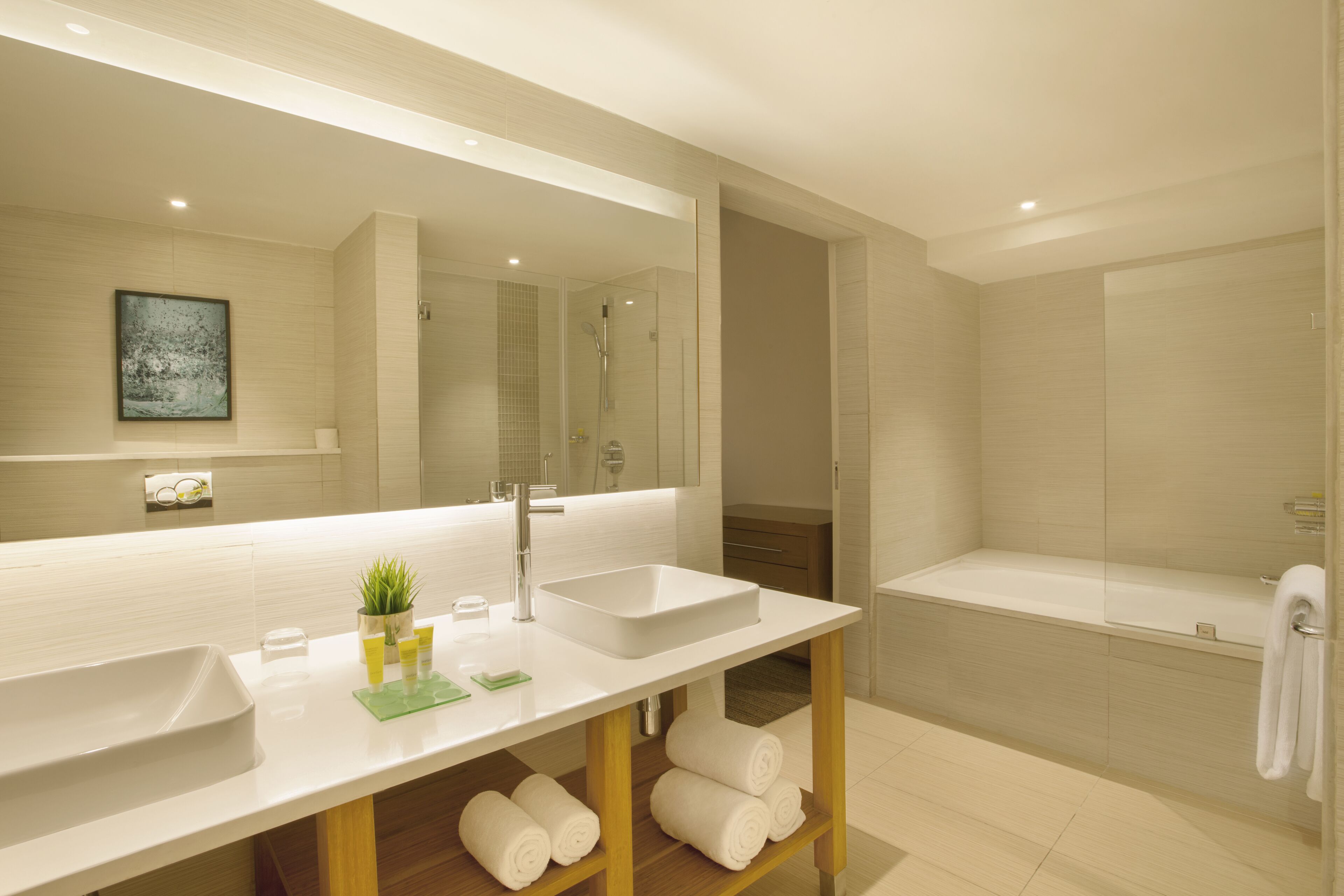 A modern bathroom with two sinks, a large mirror, a shower, and a bathtub.