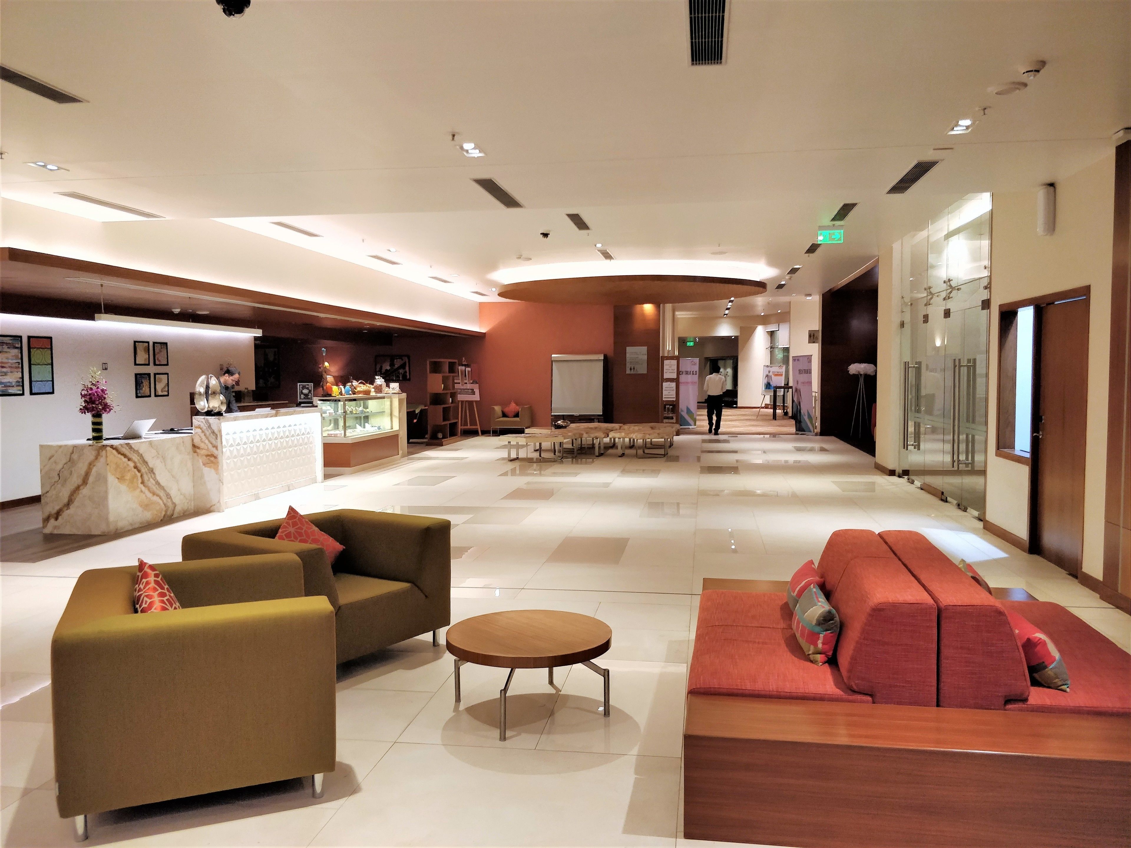Un hall amplio con mostrador de recepción, sofás y una mesa de centro.