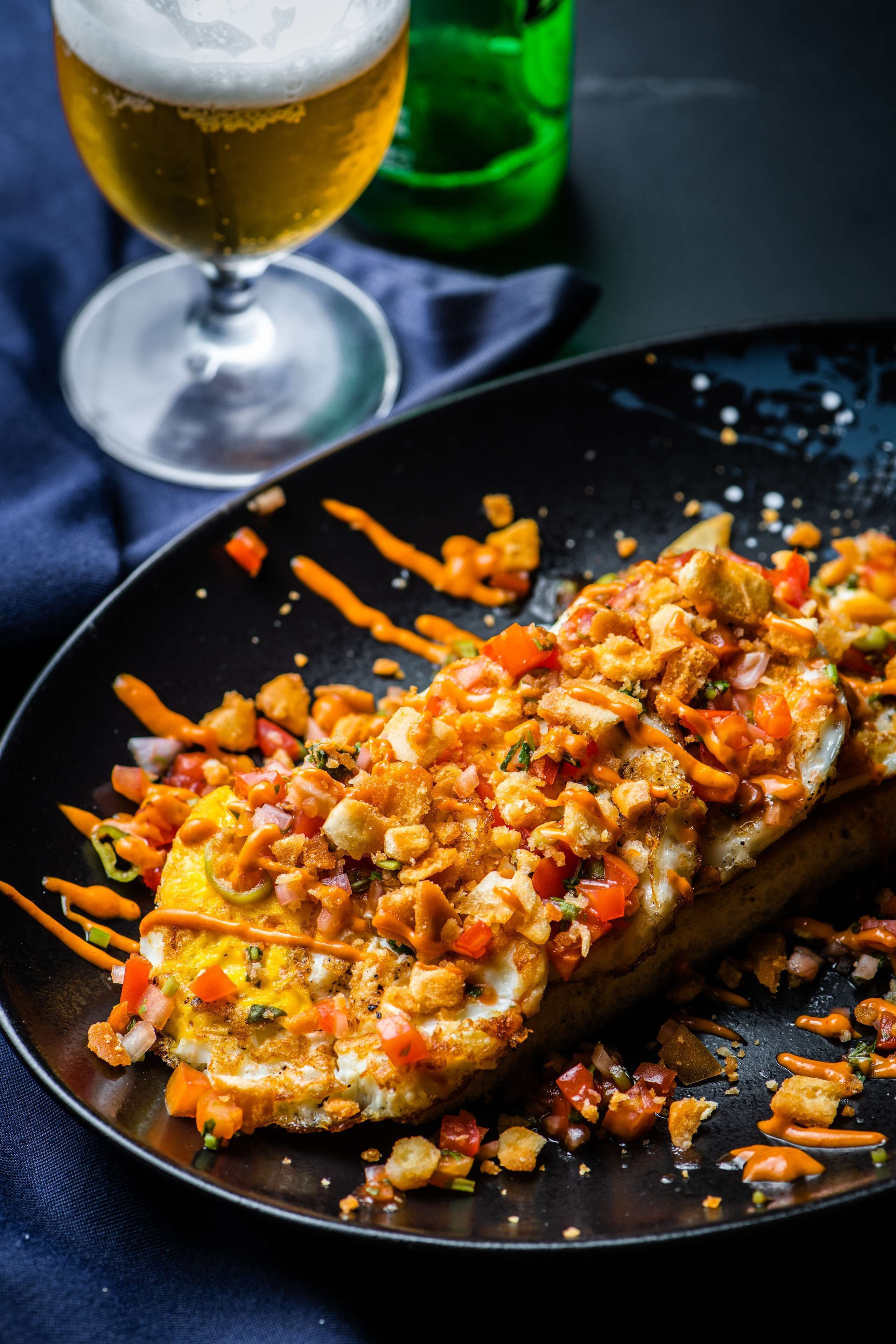 Plat amb un ou de truita, tomàquets daurat i formatge esmicolat sobre un plat negre.