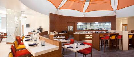 A modern restaurant with a central bar, multiple dining tables, and orange canopy overhead.