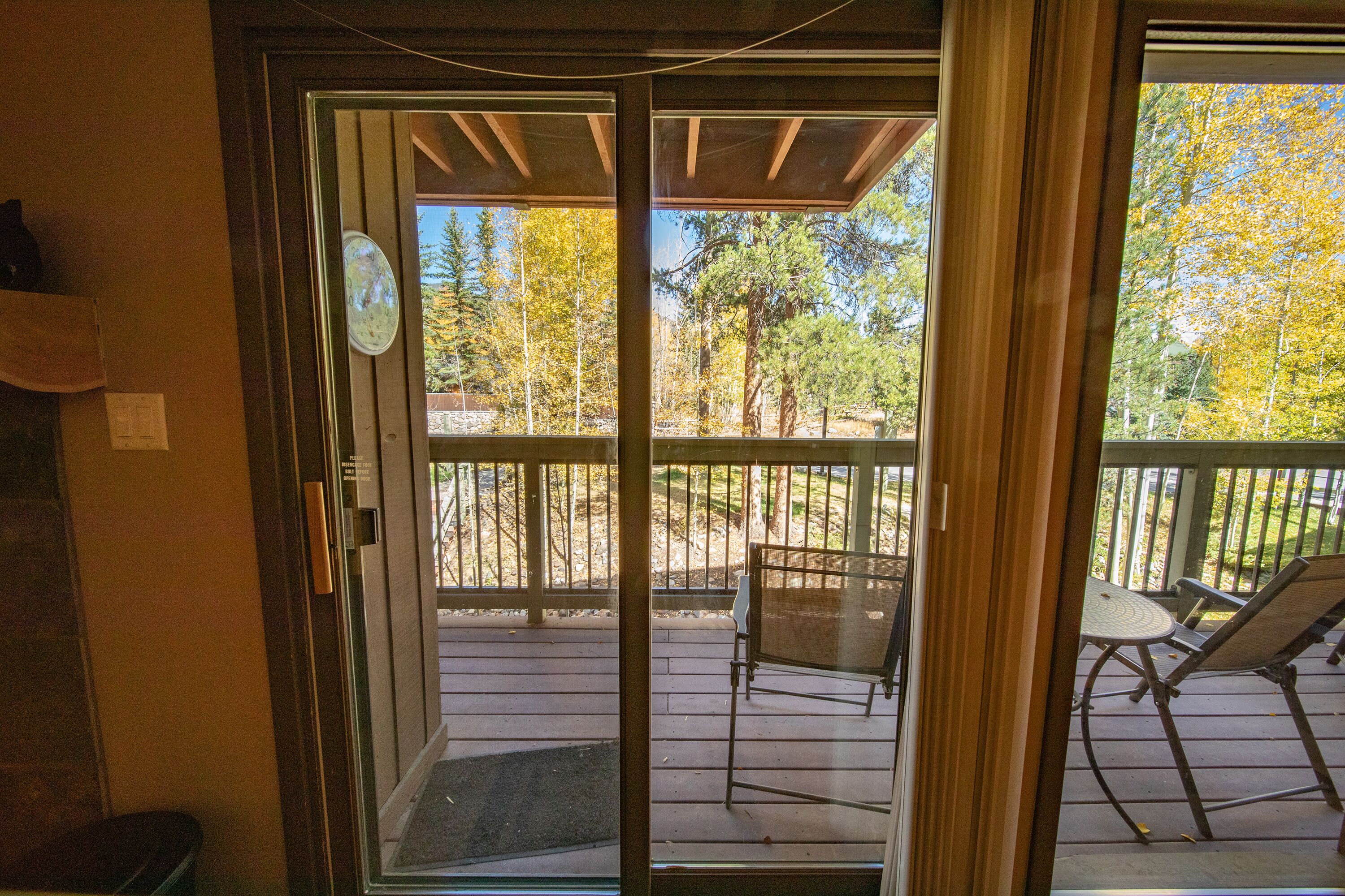 A sliding glass door leading to an outdoor deck with a table and chairs.