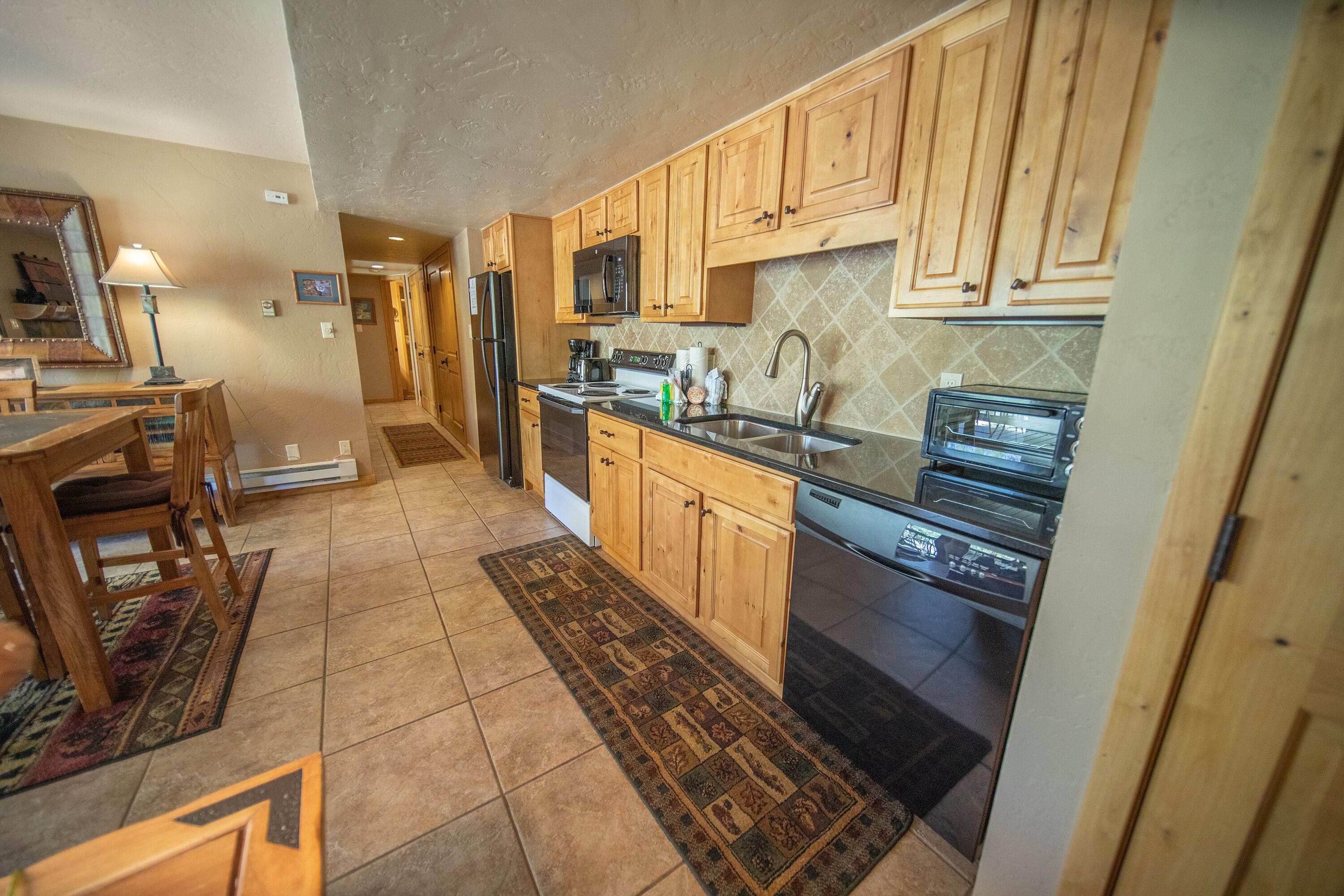 A kitchen with wooden cabinets, a microwave, a toaster, and a dishwasher.
