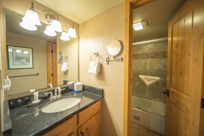 A bathroom with a sink, mirror, towel rings, and a shower area. - Wild Irishman 1043 (Keystone)