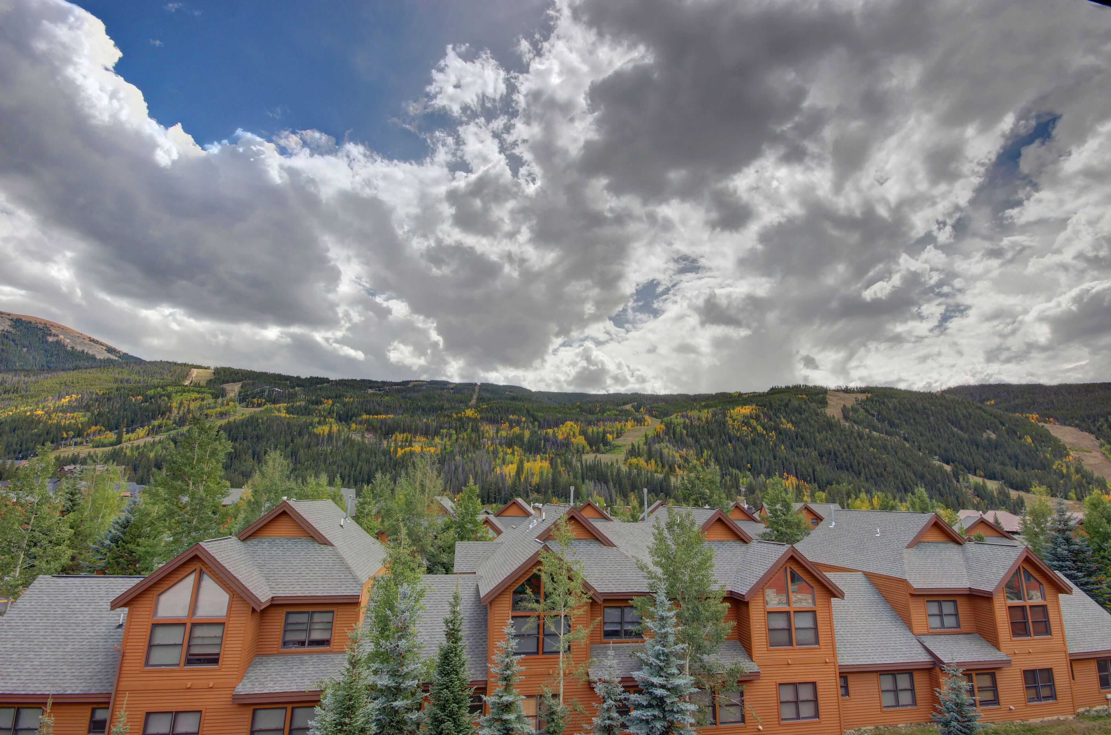 A row of log cabin-style buildings with a mountainous backdrop.