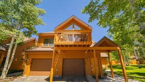 Une maison à deux étages avec une façade en bois, un porche à l’avant et un garage.