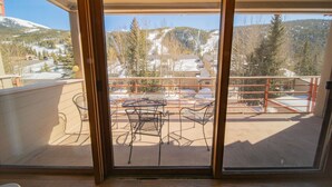 A balcony with metal chairs and a table, overlooking a snowy mountain landscape. - Ski Run 202 (Keystone)