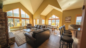 A spacious living room with a large sectional sofa, a dining area, and a kitchen with a bar.