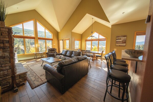 A spacious living room with a large sectional sofa, a dining area, and a kitchen with a bar.