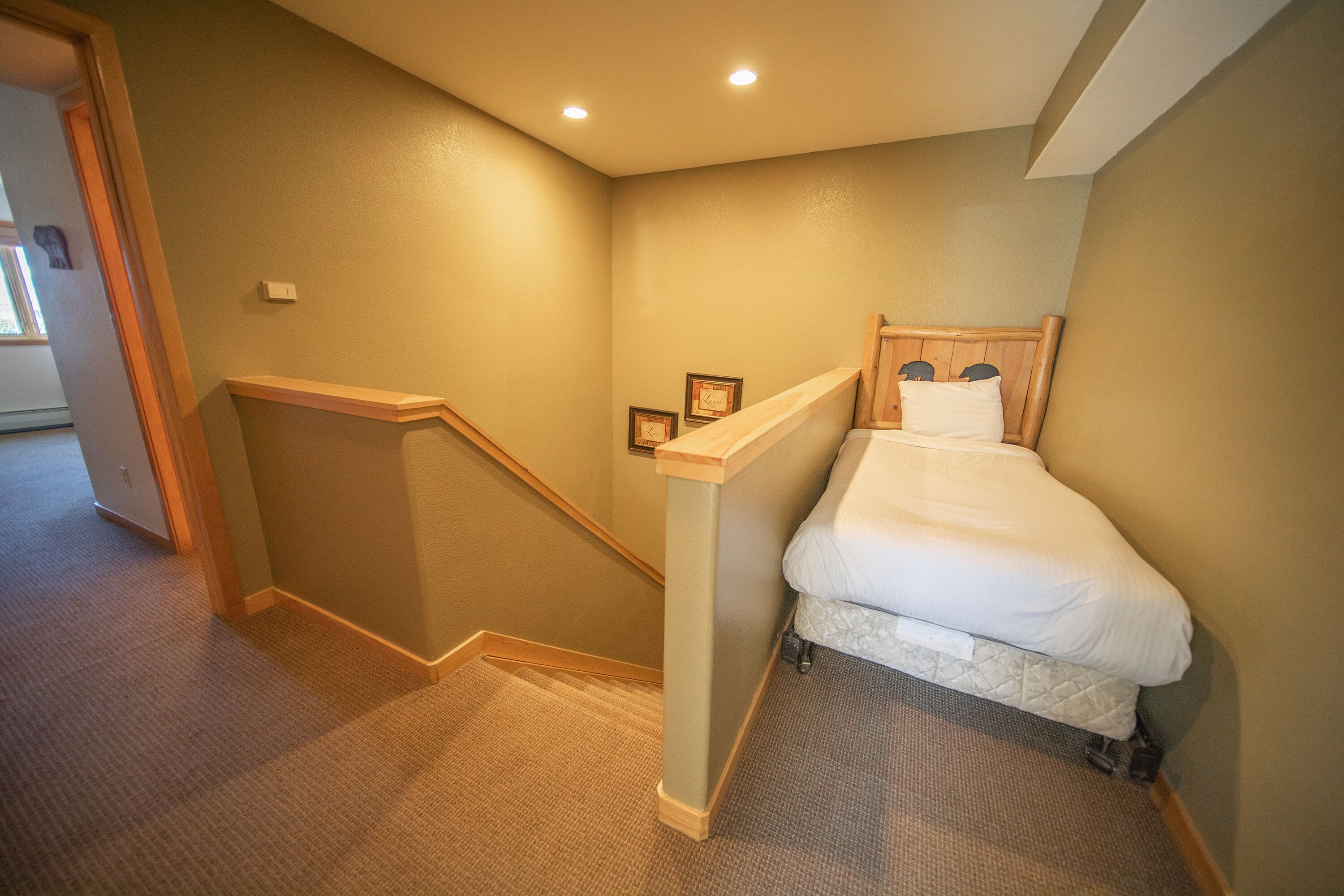 A bedroom with a bed, wooden headboard, and a small bedside table with a framed picture.