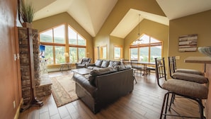 A spacious living room with a large sofa, dining area, and a stone fireplace.