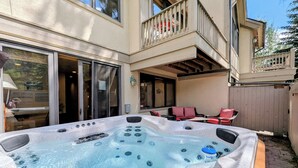 A hot tub in a backyard with a patio area, a dining table, and outdoor seating.