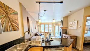 A modern kitchen with a central island, stainless steel appliances, and a large window providing natural light. - Silver Mill 8156 (Keystone)