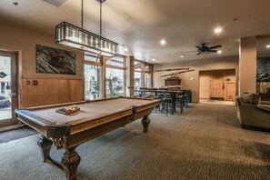Relax in a spacious indoor area with a pool table, staircase, and artwork-adorned walls.