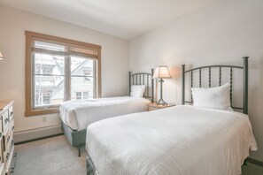 A bedroom with two beds, a window, and a dresser. - Black Bear 8052 by SummitCove Vacation Lodging (Keystone)