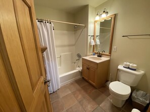 A bathroom with a shower, toilet, sink, and mirror.
