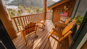 A wooden deck with wooden chairs and a view of a snowy mountain landscape.