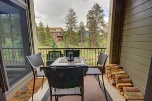 A balcony with a table and chairs, overlooking a forest and a building. - Pines 2047 (Keystone)
