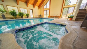 An indoor swimming pool with a stone deck, wooden beams, and potted plants. - Enclave 12 (Keystone)