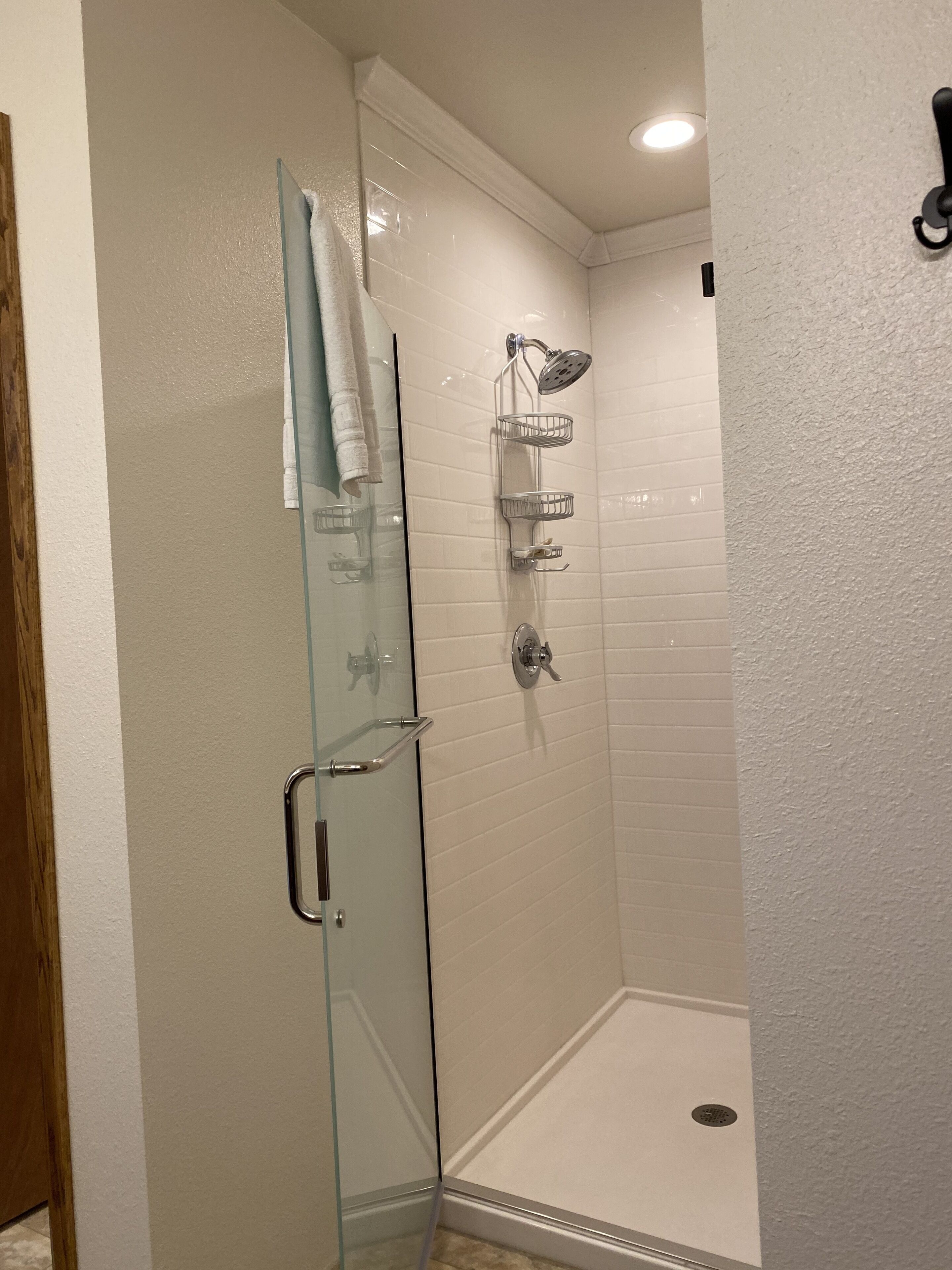 A bathroom with a glass shower enclosure, a towel rack, and a toilet.