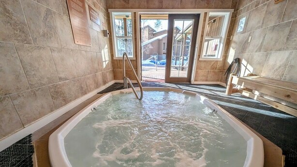 Ein Whirlpool in einem Raum mit gefliesten Wänden und Blick ins Freie.