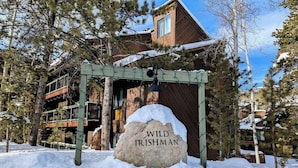 Ein verschneiter Außenbereich mit einer Holzhütte und einem Schild mit der Aufschrift 'WILD IRISHMAN'.
