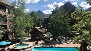Un espace piscine comprenant un jacuzzi, des chaises longues et un petit chalet.