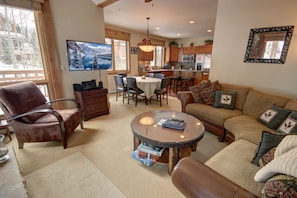 A cozy living room with a fireplace, a dining area, and a kitchen. - Settlers Creek 6535 (Keystone)