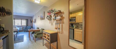 A compact living space with a kitchenette, a dining area, and a mirrored wall reflecting the kitchen.